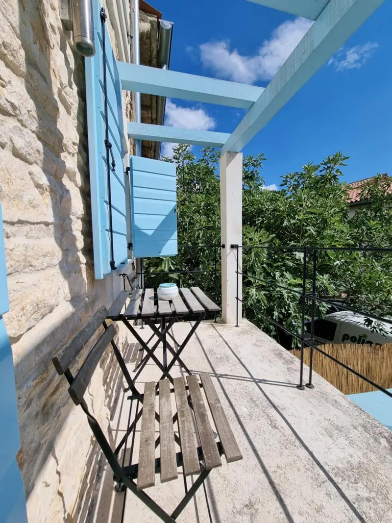 Balkon von Casa Bella mit Klapptisch unter der Pergola und Blick ins Grüne