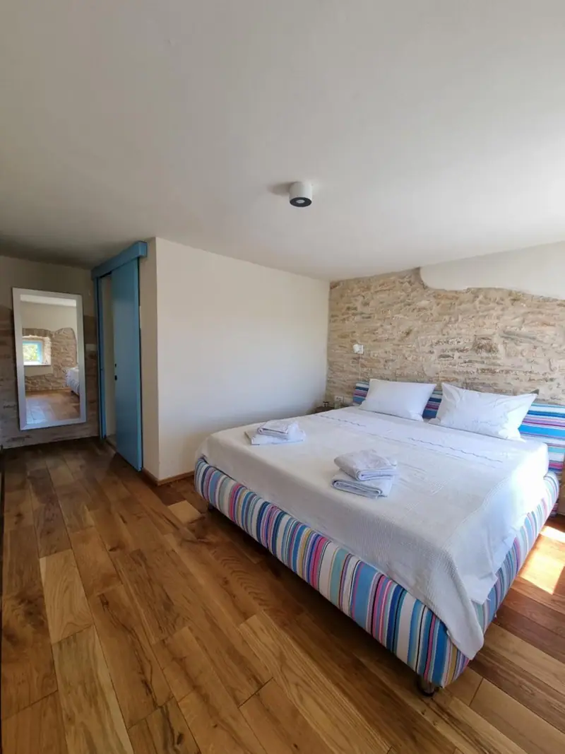 Schlafzimmer mit Doppelbett vor einer Natursteinwand