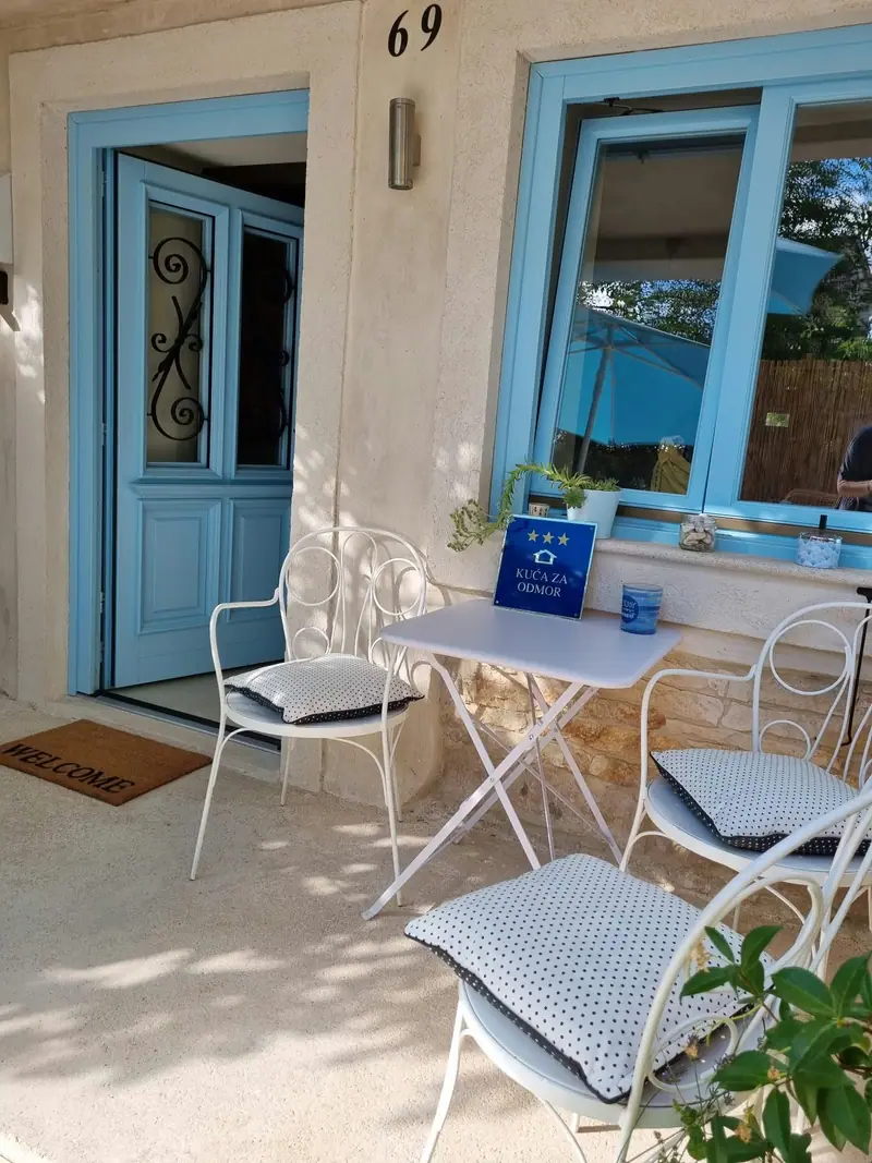Sitzgarnitur mit weißem Bistrotisch und Stühlen vor der Eingangstür von Casa Bella