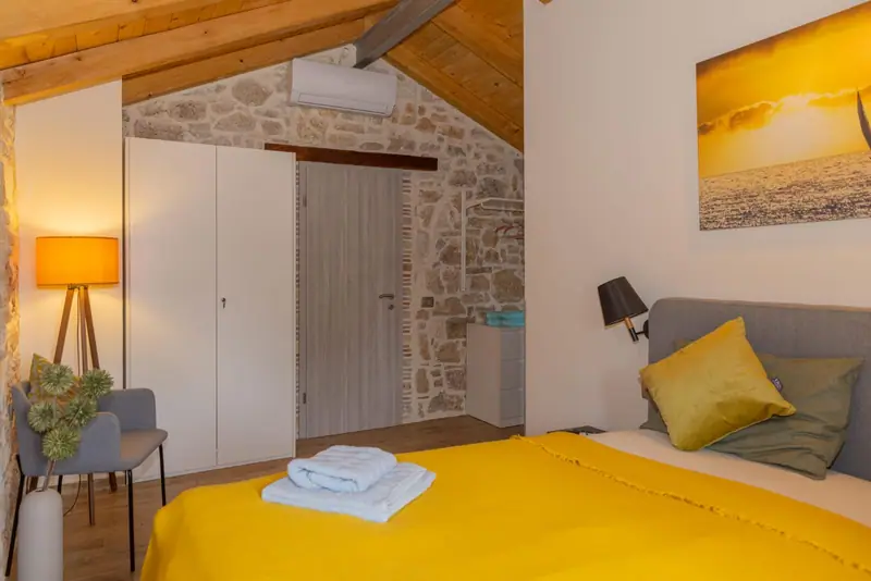 Bedroom with box spring bed under a wooden beamed ceiling