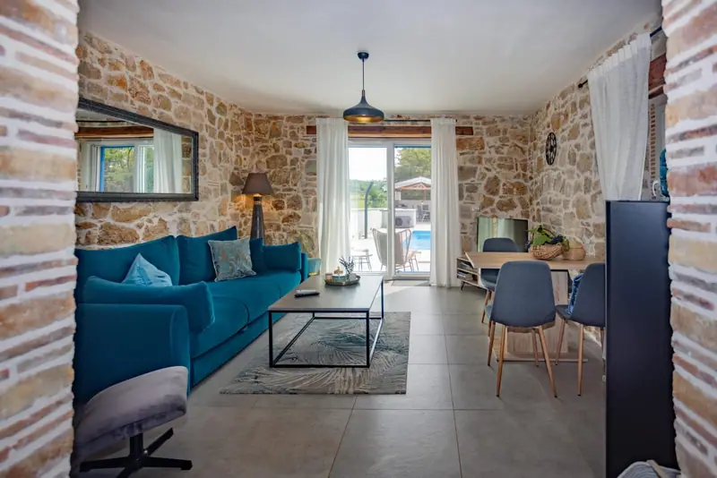 Living room with sofa and natural stone wall, view of the terrace door