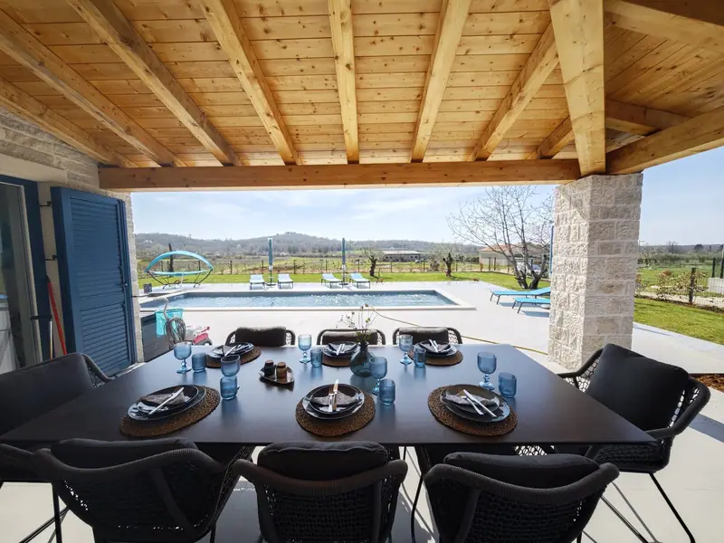 Covered terrace with large dining table and view of the pool