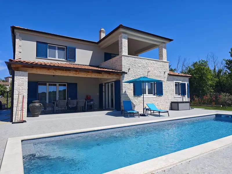 Villa Majuli from the front: natural stone house with blue shutters, terrace and pool