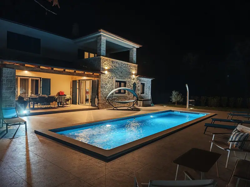 Illuminated pool at night in front of the terrace